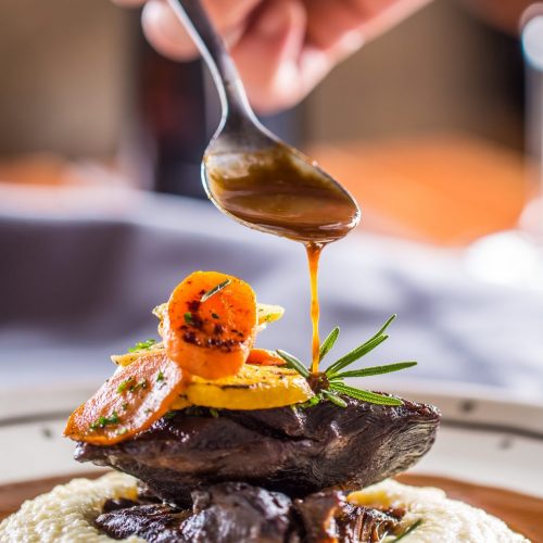 Chef in pub or restaurant decorates portion of the meal in pup or restaurant.